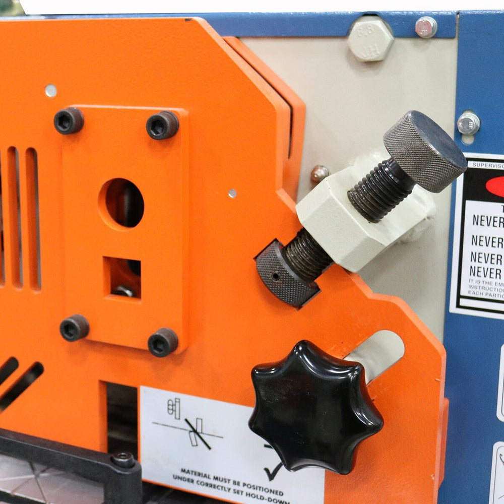 Close-up of an orange machine with control knobs and warning labels.