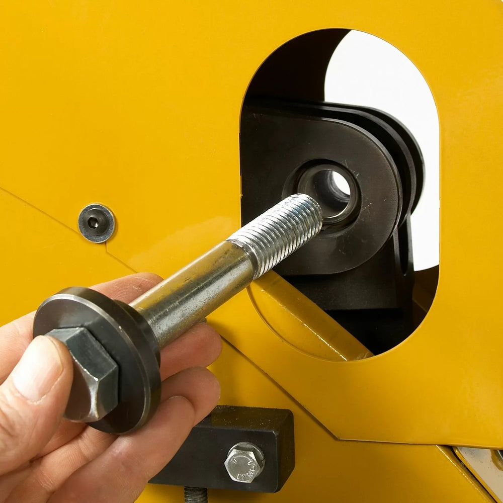 Hand using a tool to adjust a yellow machine with a circular component.