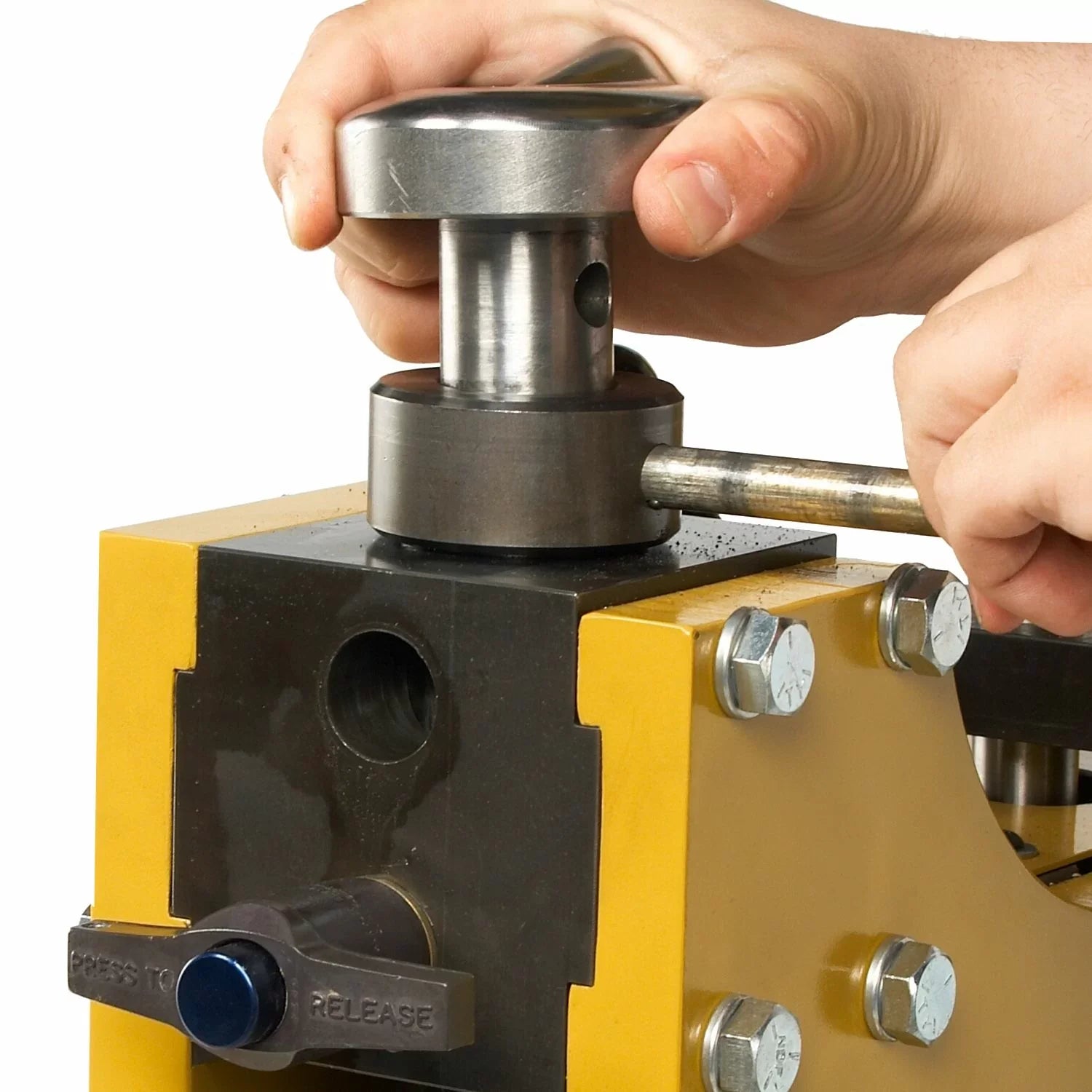 Hand using a metal tool on a yellow machine with a white background
